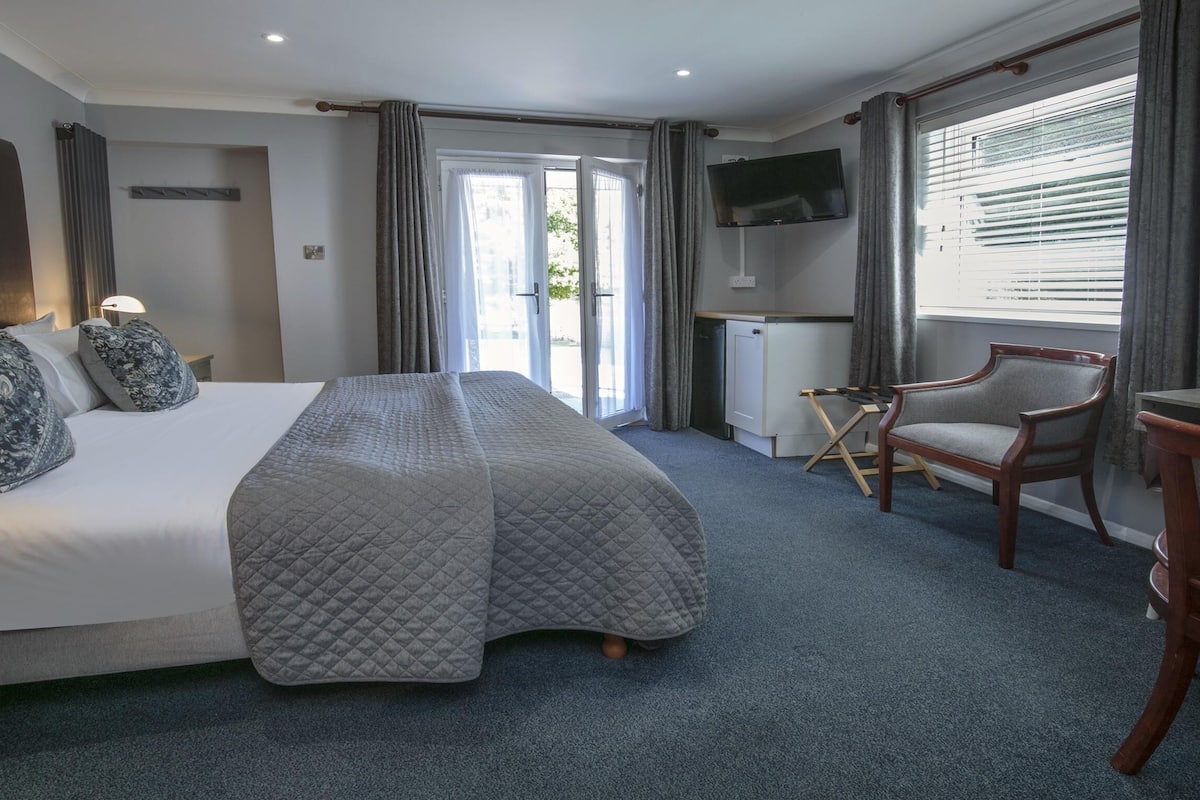 A hotel room with a bed, a TV, a desk, and a chair.