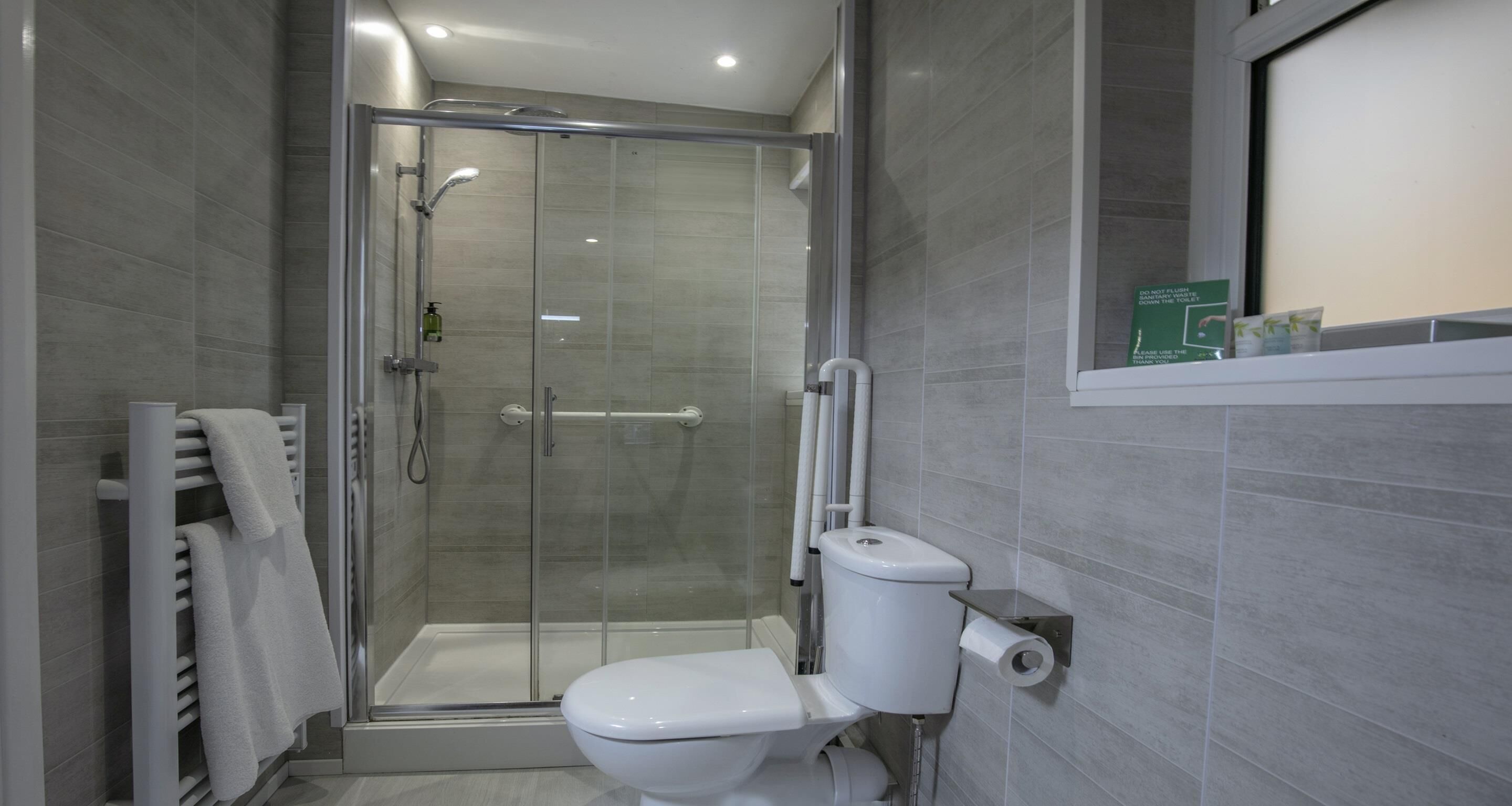 A modern bathroom with a glass-enclosed shower, a white toilet, and a towel rack.