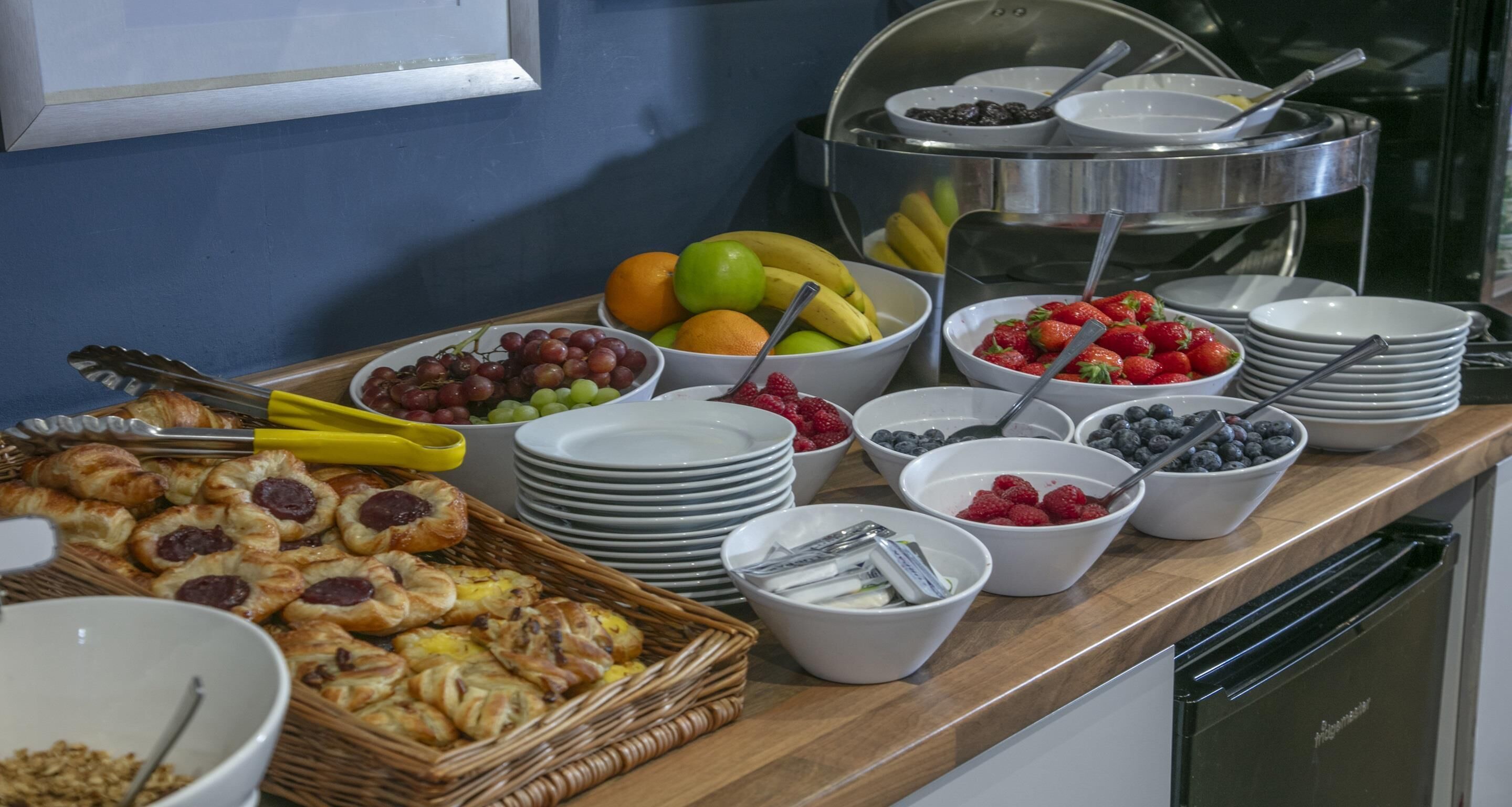Uma mesa de buffet com diversas frutas, bagas e doces.