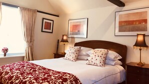 A neatly made bed with a patterned bedspread, two bedside lamps, and a framed picture on the wall. - The Blue Cow (Huntingdon)