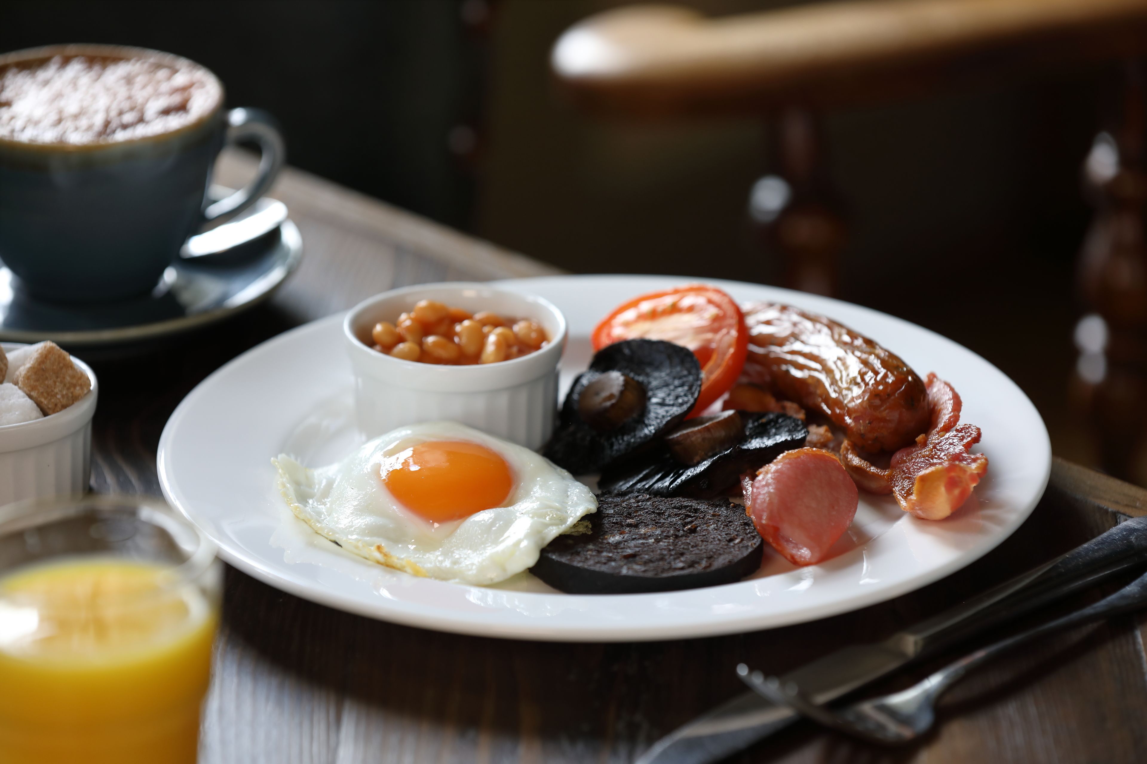 A breakfast plate with eggs, beans, tomatoes, and sausages.