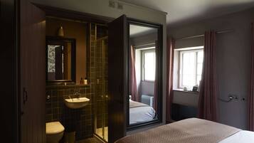Habitación de hotel con cama, baño con lavabo e inodoro, y un espejo grande.