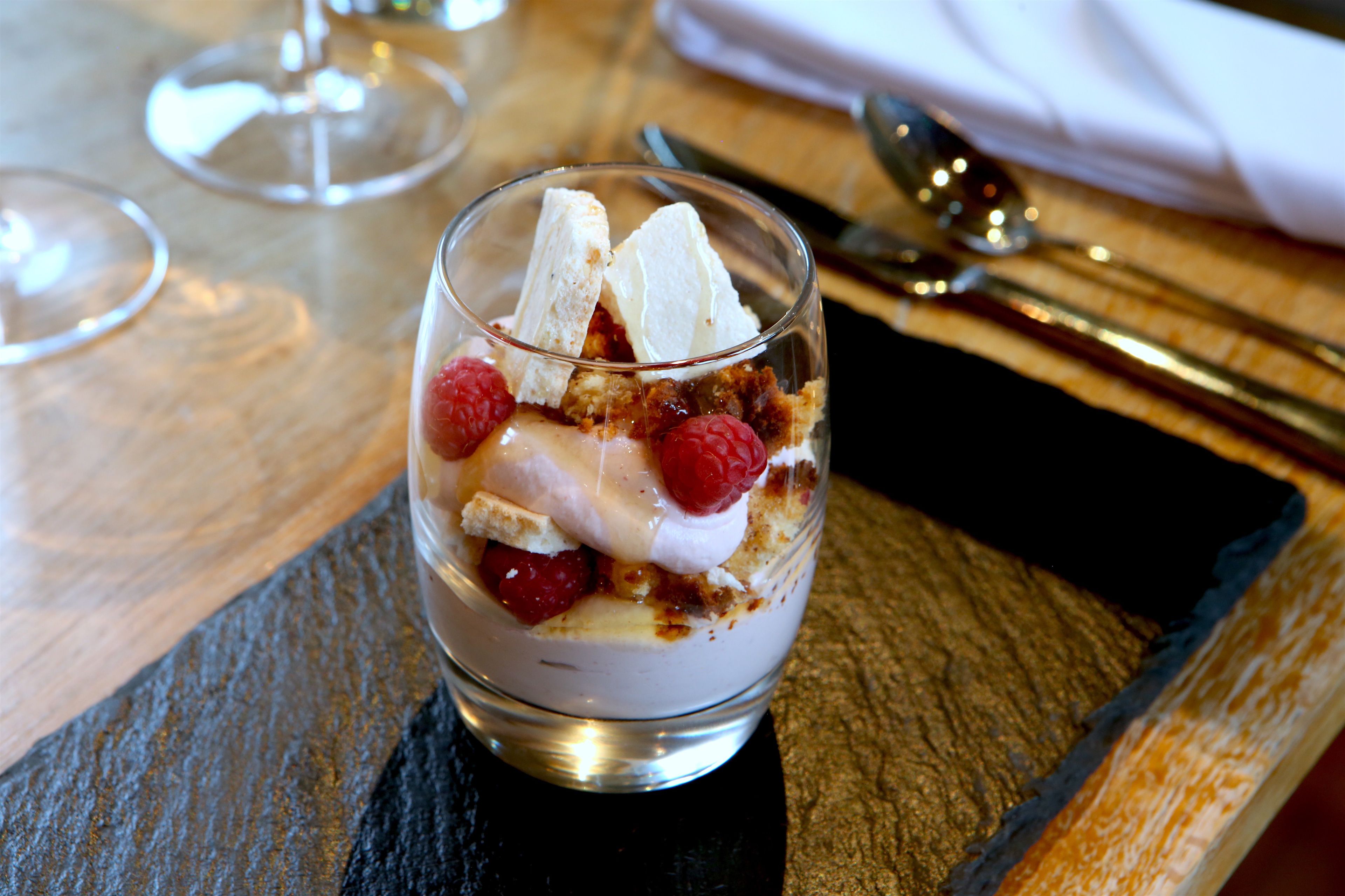 Un dessert servi dans un verre, présenté sur un plateau en ardoise.