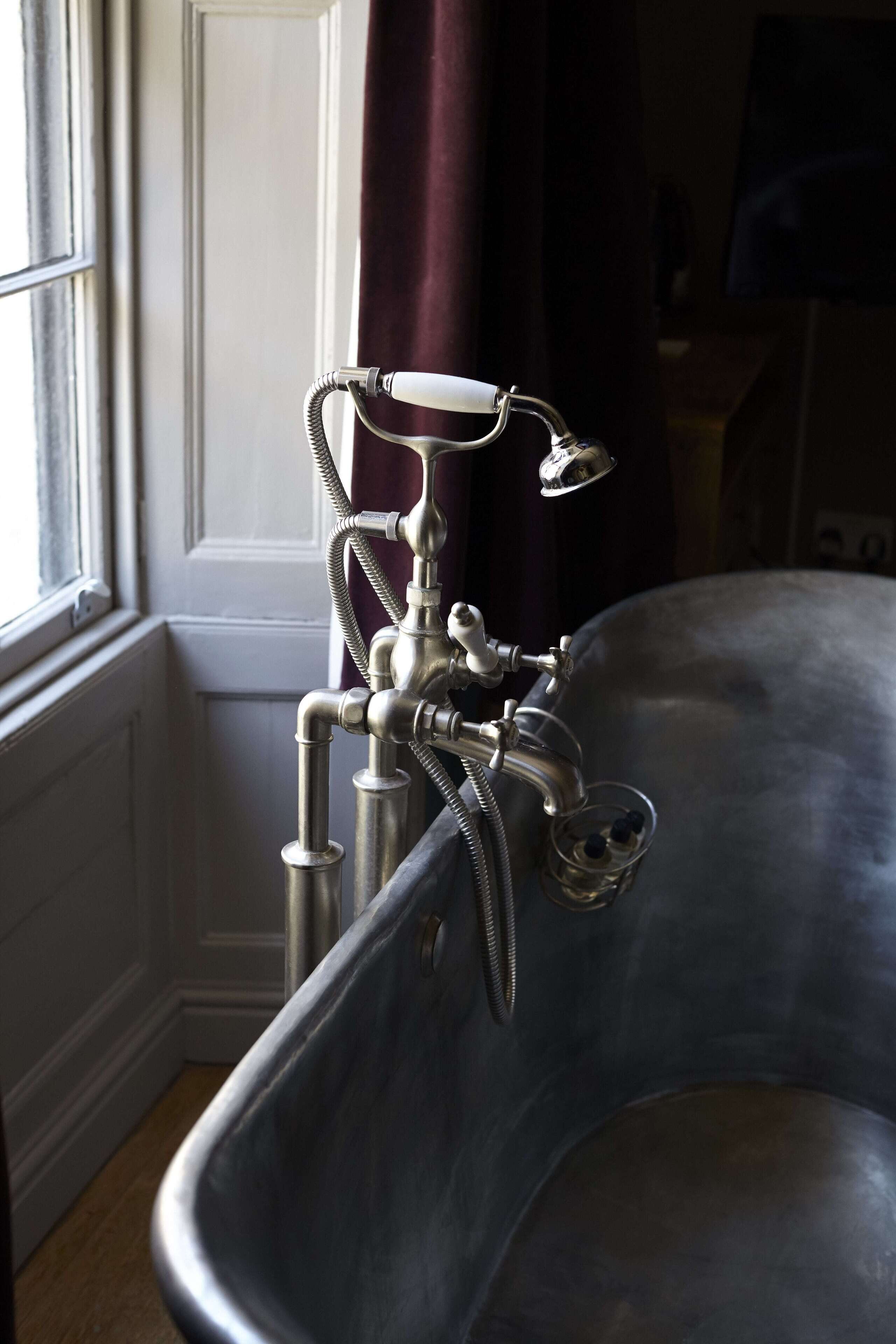 A vintage-style bathtub with a faucet and a glass container.