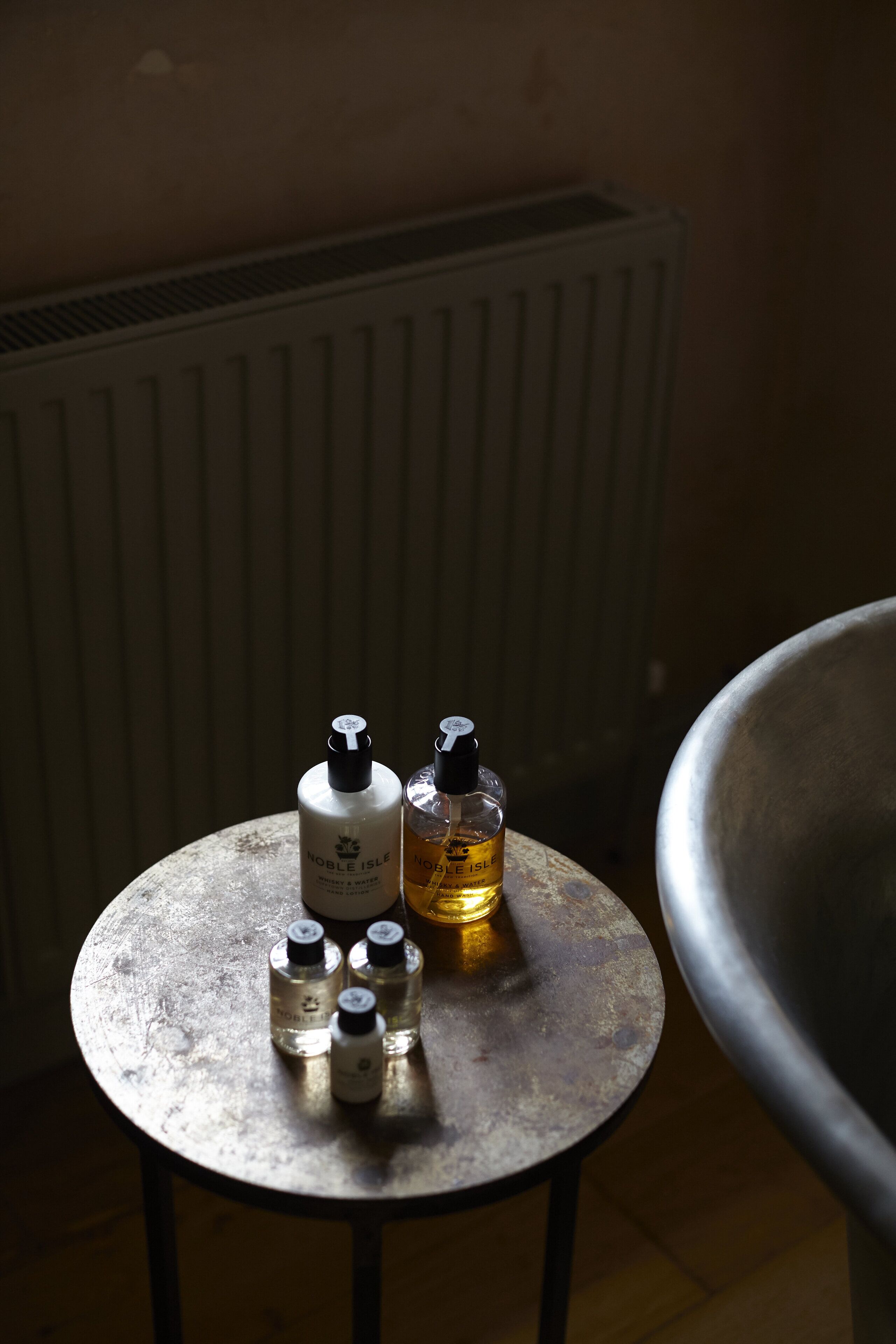 A round metal table with four bottles of skincare products.
