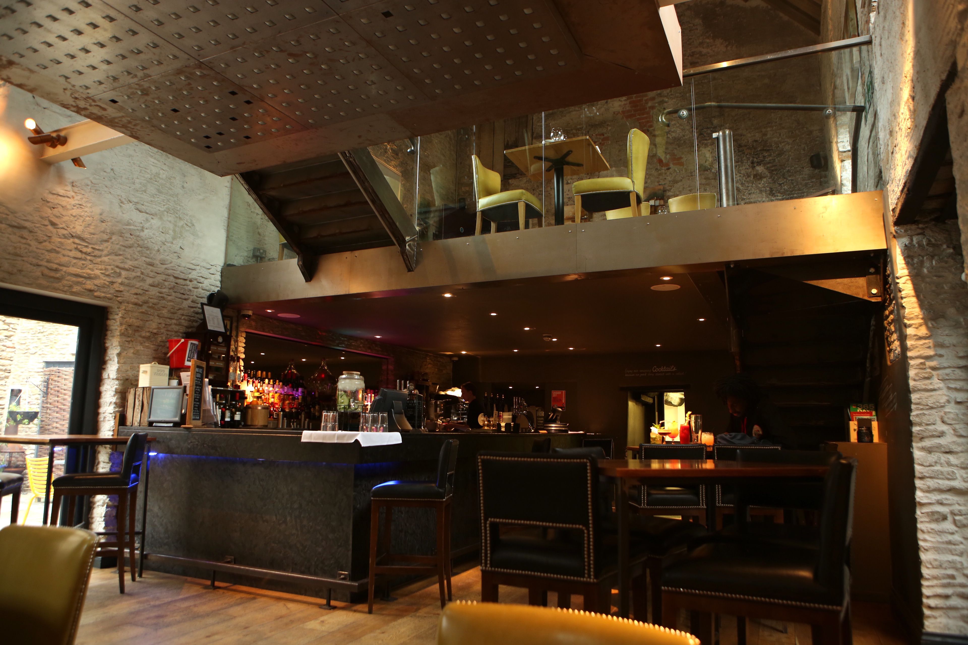 A bar area with a counter, stools, and a seating area with chairs.