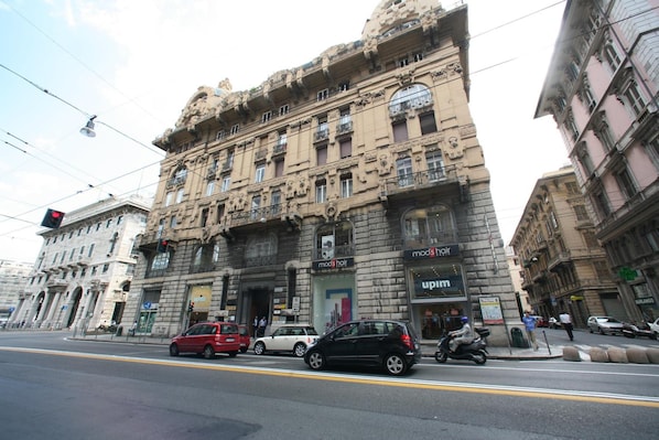 A historic building with ornate architecture, a storefront with a 'mod's hair' sign, and a 'upm' sign. - Hotel Barone (Genoa)