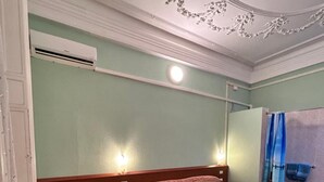 A room with two beds, a bathroom, and a ceiling with decorative molding. - Hotel Barone (Genoa)