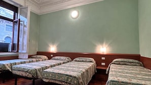 A room with four beds arranged in a row, a large window with a view, and a decorative ceiling. - Hotel Barone (Genoa)