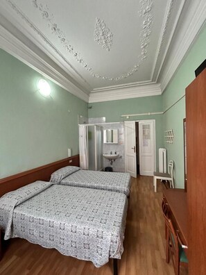 A room with two beds, a wooden desk, a mirror, and a wardrobe. - Hotel Barone (Genoa)