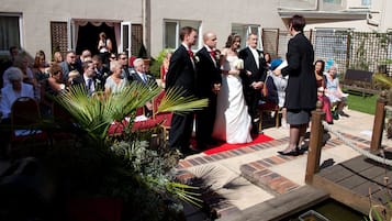 Una cerimònia de casament a l'aire lliure, amb convidats asseguts en cadires vermelles.