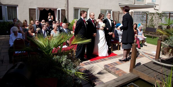 Una ceremonia de boda al aire libre con invitados sentados en sillas rojas.