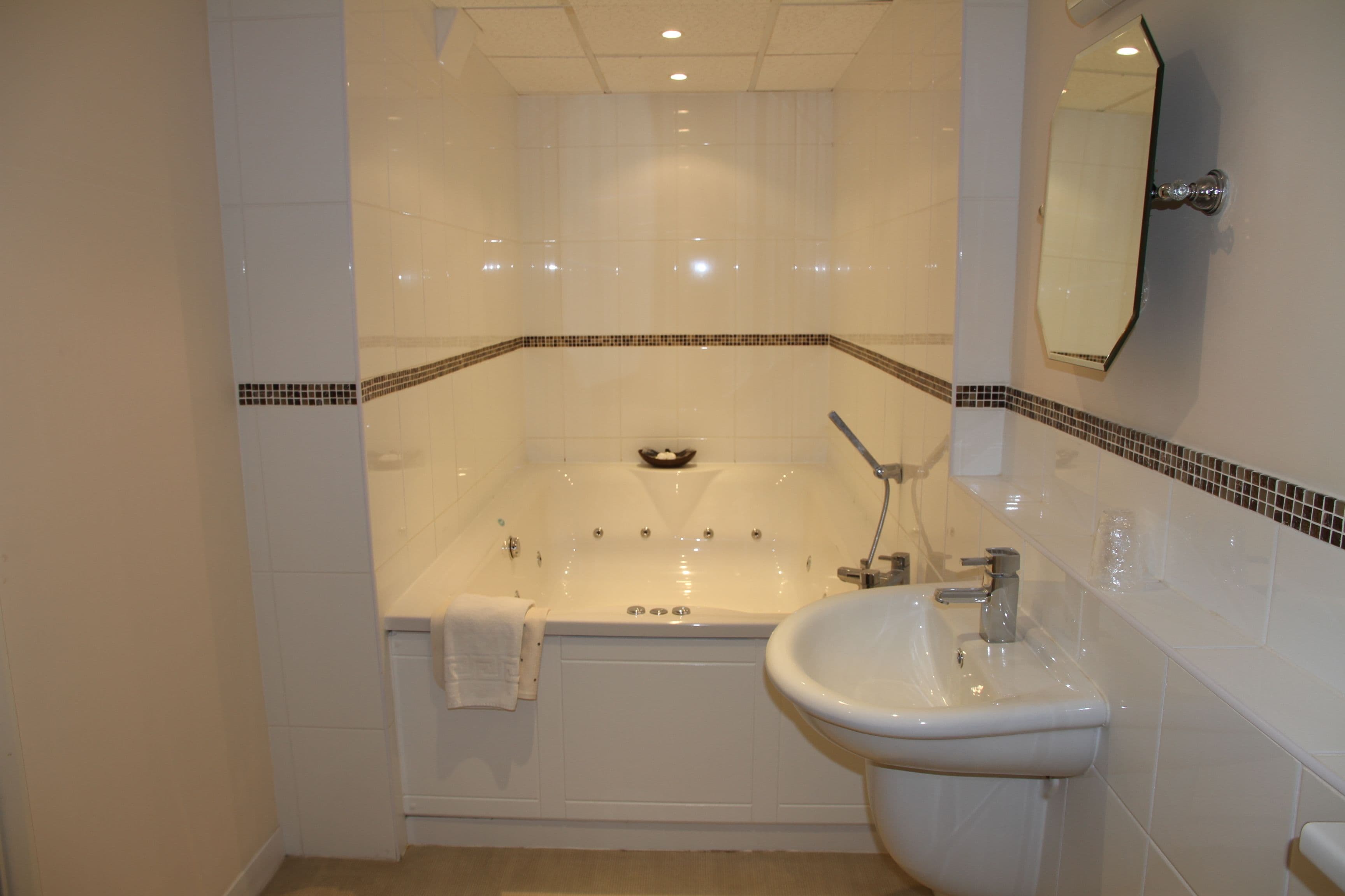 A bathroom with a bathtub, a sink, and a mirror.