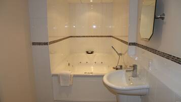 A bathroom with a bathtub, a sink, and a mirror.