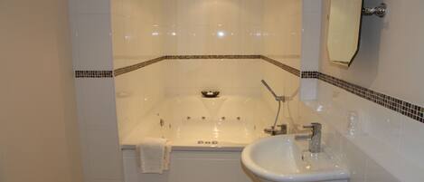 A bathroom with a bathtub, a sink, and a mirror.