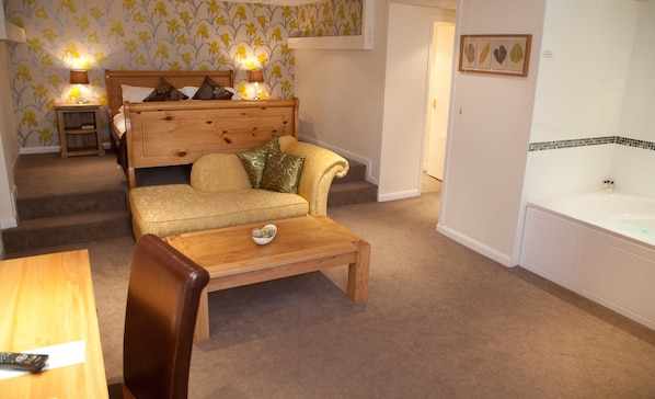 A cozy living room with a sofa, a wooden coffee table, a fireplace, and a bathtub. - King Charles Hotel (Gillingham)