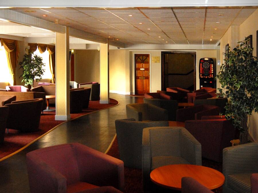 Eine Lobby mit Sitzbereichen, einem Empfangsbereich und einer großen Pflanze.