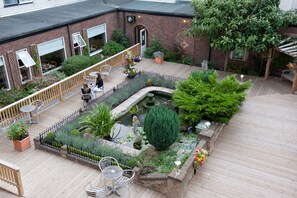 A courtyard with a wooden deck, seating areas, a small pond, and various plants. - King Charles Hotel (Gillingham)