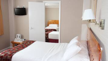 Ein Hotelzimmer mit einem Bett, einem Nachttisch mit Lampe und einem an der Wand befestigten Fernseher.