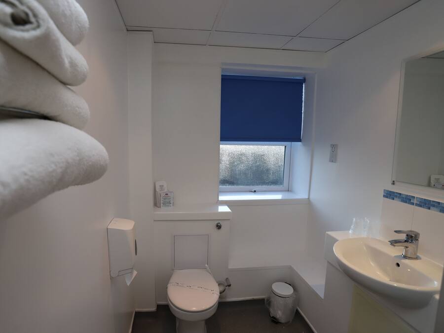 A small, compact bathroom with a toilet, sink, and window.