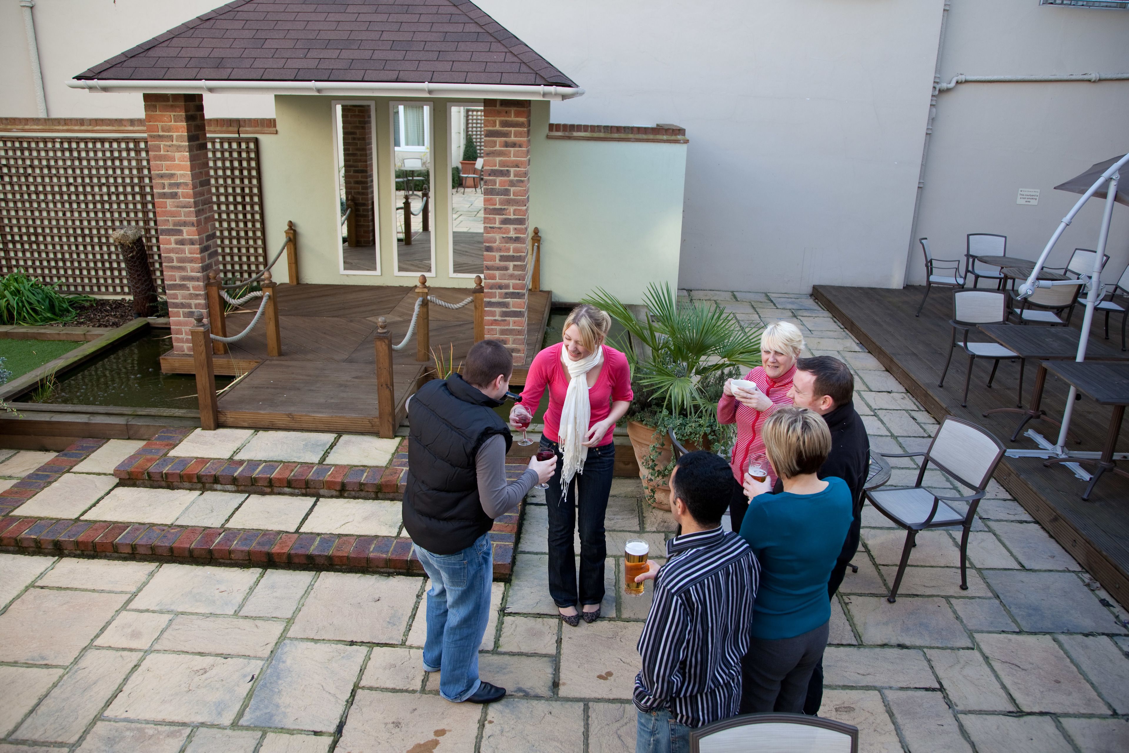 A courtyard with a brick building, outdoor seating, and a small pool.