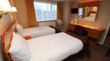 A hotel room with two beds, a desk, a mirror, and a window with curtains.