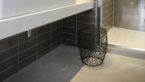 A modern bathroom with a large mirror, a white sink, and a glass shower enclosure.