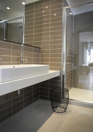 A modern bathroom with a large mirror, a white sink, and a glass shower enclosure. - Ca' D'andrean (Riomaggiore)