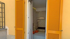 A room with a bed, a small desk, and a window with shutters.
