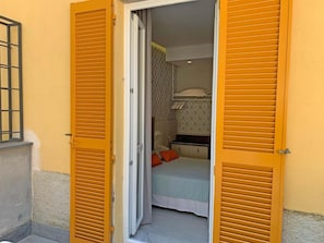 A room with a bed, a small desk, and a window with shutters. - Ca' D'andrean (Riomaggiore)