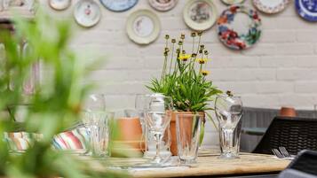 A dining table with a potted plant and several glasses of water.