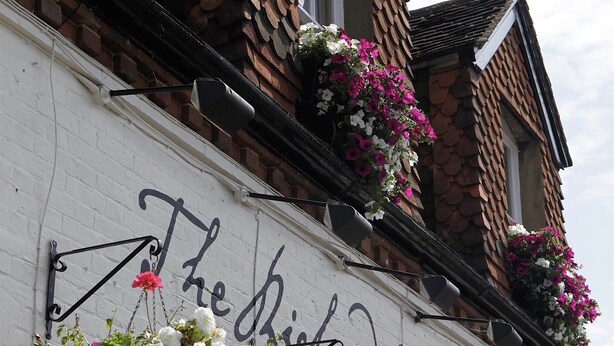 Un edificio con un cartel que dice "The Richard's Inn" y macetas colgantes de flores.
