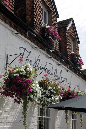 A building with a sign reading "The Richard's Inn" and hanging flower baskets. - The Richard Onslow (Cranleigh)