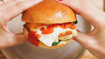 A sandwich held by hands over a plate.