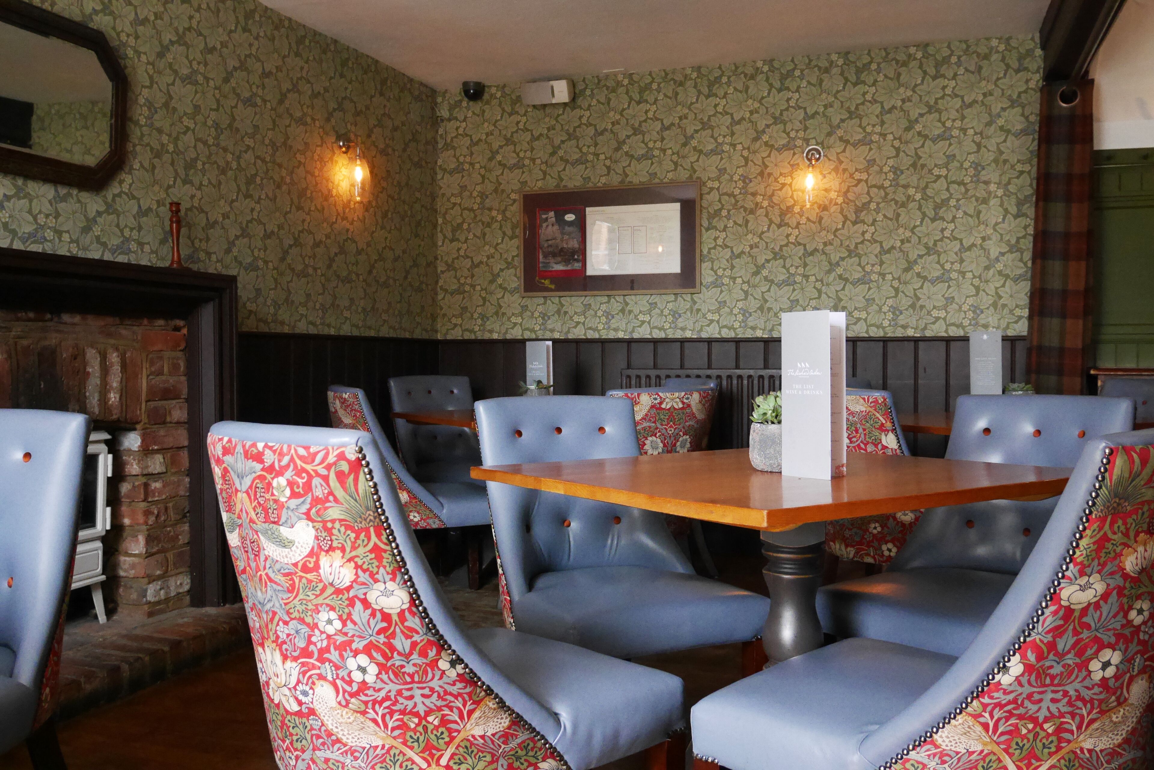 A dining area with a wooden table and blue upholstered chairs with floral patterns.