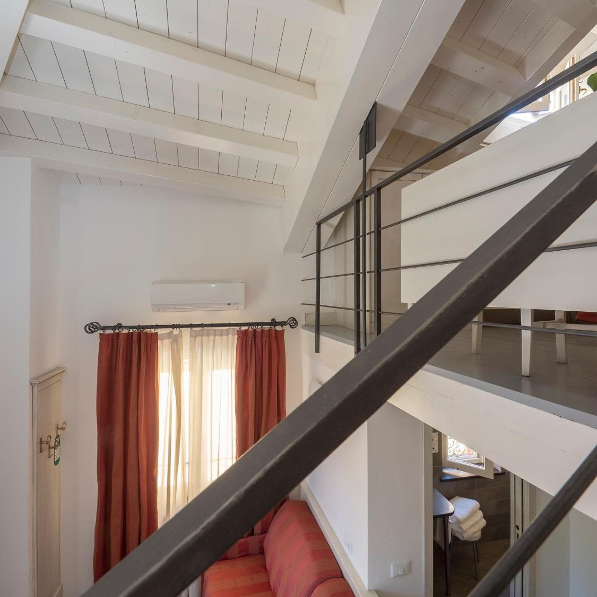 Un interno su più livelli con una scala, un divano e un'area pranzo.