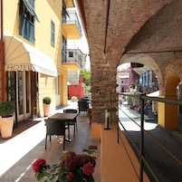 Un patio de hotel con mesas al aire libre, un arco de piedra y vistas a la calle.