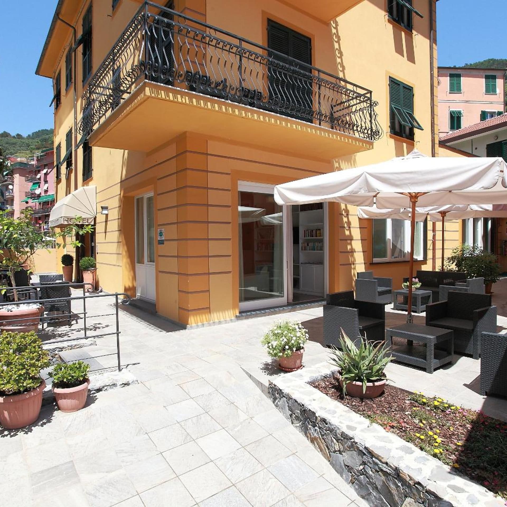 Un hotel con posti a sedere all'aperto, un balcone e un vialetto in pietra.