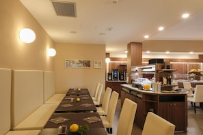 A hotel dining area with a long table set for a meal, a coffee station, and a kitchen in the background. - Margherita (Monterosso al Mare)