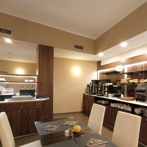 A modern hotel dining area with a central table, chairs, a coffee station, and a counter with a menu. - Margherita (Monterosso al Mare)