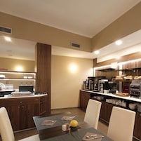 Un comedor de hotel moderno con una mesa central, sillas, una estación de café y una barra con un menú.