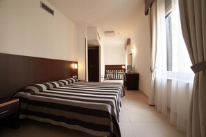 A hotel room with a large bed, a bedside table, a mirror, and a window with curtains. - Margherita (Monterosso al Mare)