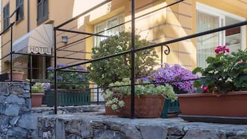 Un hotel con parete in pietra, piante in vaso e ringhiera da balcone.