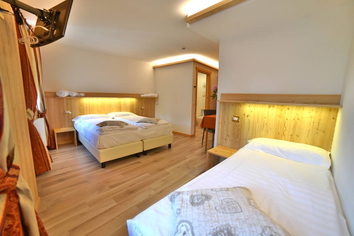 A hotel room with two beds, wooden flooring, and a wooden headboard.