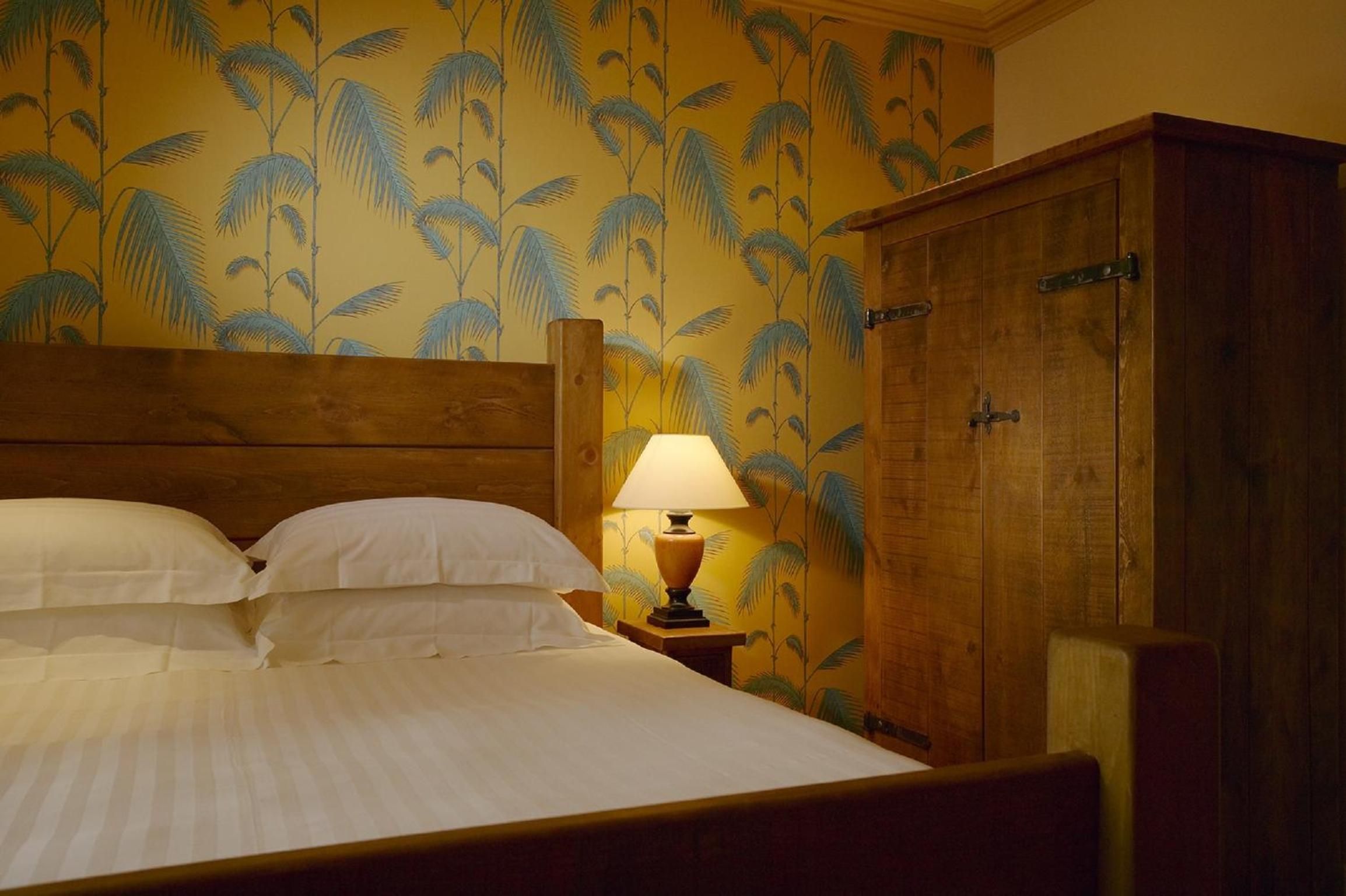 Una camera d'albergo con un letto, un comodino con una lampada e un armadio.