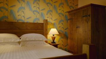 Una camera d'albergo con un letto, un comodino con una lampada e un armadio.
