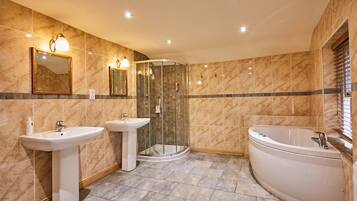 A bathroom with two sinks, a glass-enclosed shower, and a freestanding bathtub.