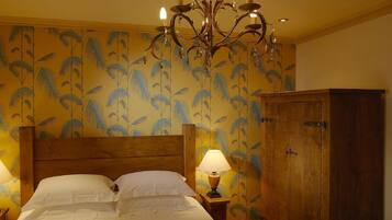 A bedroom with a wooden bed, a chandelier, a nightstand with a lamp, and a wardrobe.