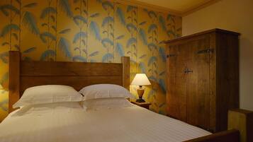 A hotel room with a bed, a nightstand with a lamp, and a wooden wardrobe.