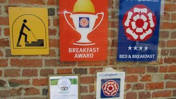 A wall with multiple signs, including a yellow sign with a person digging, a red sign with a trophy labeled 'Breakfast Award', and a blue sign with a flower and stars labeled 'Bed & Breakfast'.